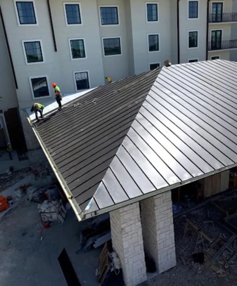 Crew installing standing seam metal roof panels on a commercial project in Temecula